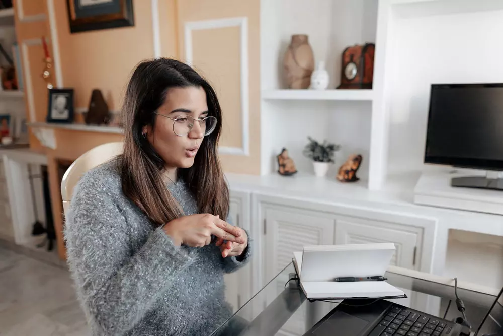 Joven comunicándose por lengua de signos mediante una videollamada de trabajo