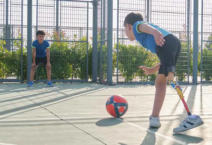 Niño con prótesis en la pierna jugando a fútbol con su hermano